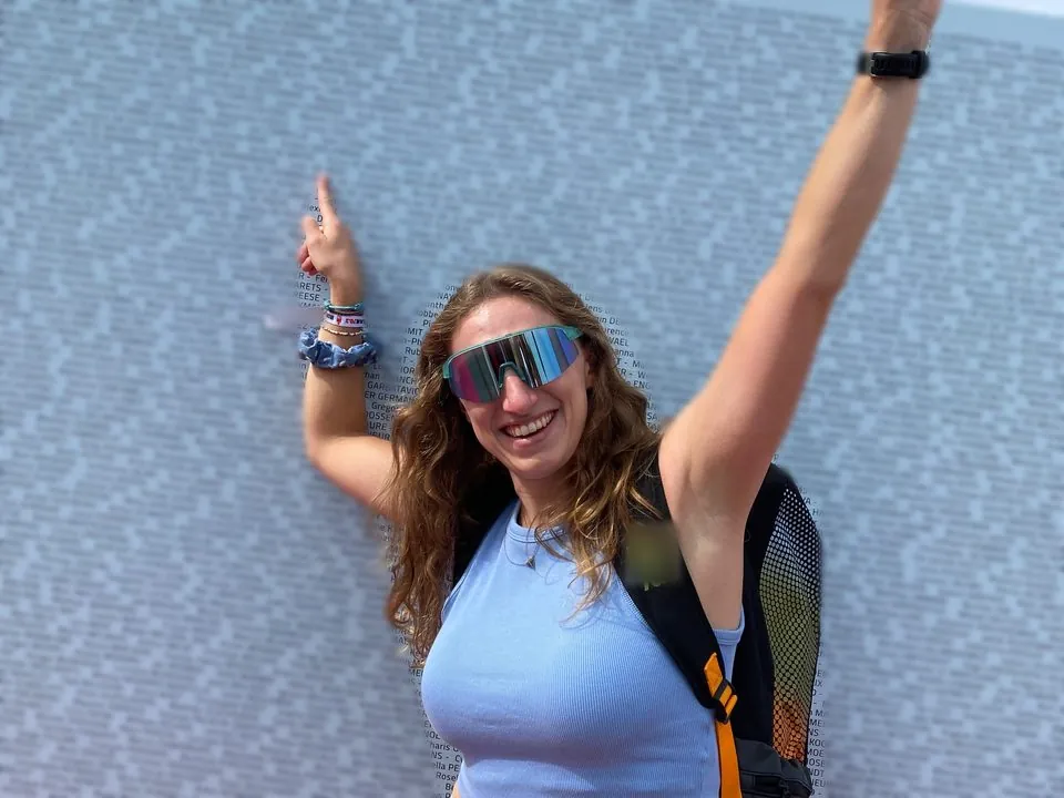 Julie, bras levés, montre son nom sur le mur des finishers